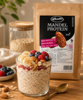 Lemke Mandel Protein 1 kg with a glass of overnight oats topped with banana, berries, almonds, and peanut butter for a protein-rich breakfast.